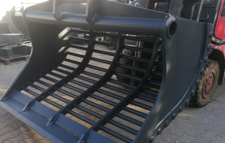 Zbliżenie ciężkiego osprzętu łyżki szkieletowej zamontowanego na ładowarce, przeznaczonego do przesiewania i oddzielania materiałów.