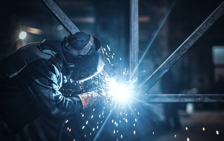 Mężczyzna spawa metalową konstrukcję.