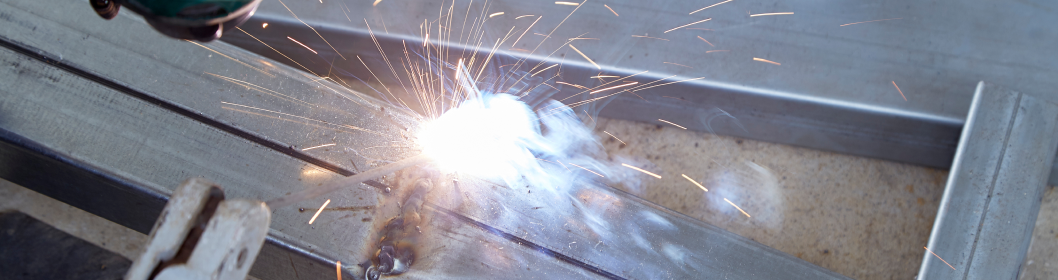 Zbliżenie procesu spawania pokazujące iskry i jasne światło podczas łączenia metalowej ramy.